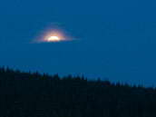 Měsíc v úplňku vychází nad lesem u osady Jizerka v Jizerských horách. Fotografováno 23. září 2010 krátce po 19. hodině. 